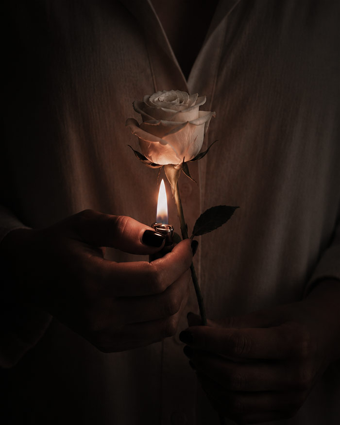 a woman hold a white rose and a lit light underneath it