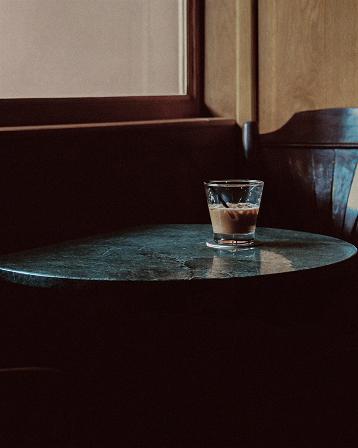 a glass of coffee sits on a green marble table acts as the perfect setting to perform a morning money magnet ritual