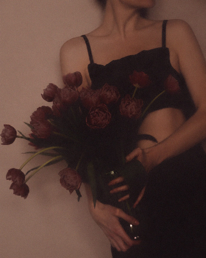a woman is holding deep read flowers implying the come to me spell was successful