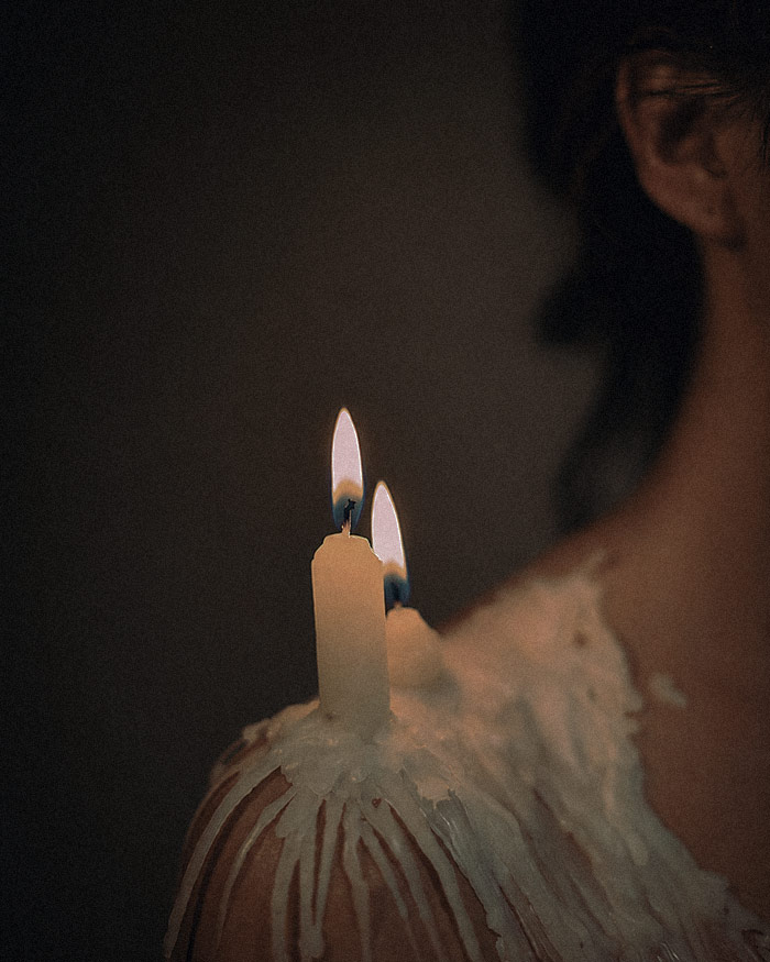 a candle dripping sits on a person's shoulder symbolizing a barrier of personal protection