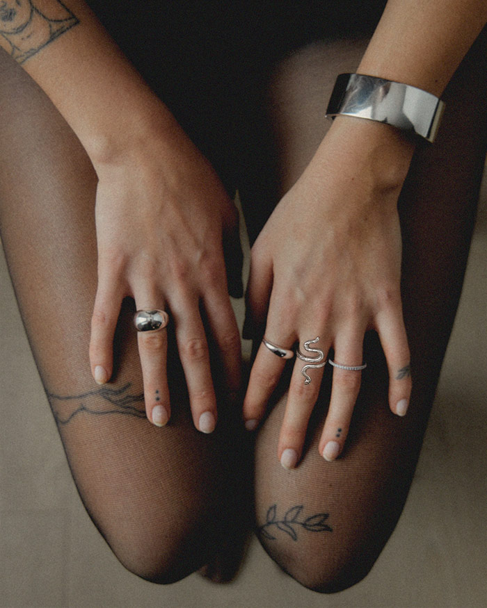 a woman's finger are adorned with silver rings that were transformed into protection jewelry