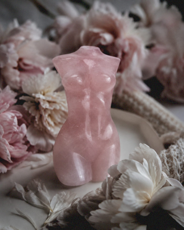 a rose quartz shaped like a female torso anchors a body image healing ritual