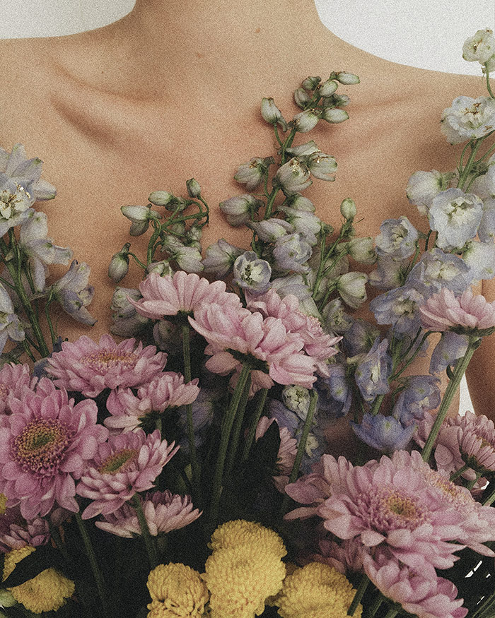 the energy of various flowers cover the bare chest of a woman to assist in body image healing