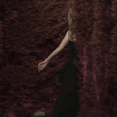 a woman with long brown hair in the shadows
