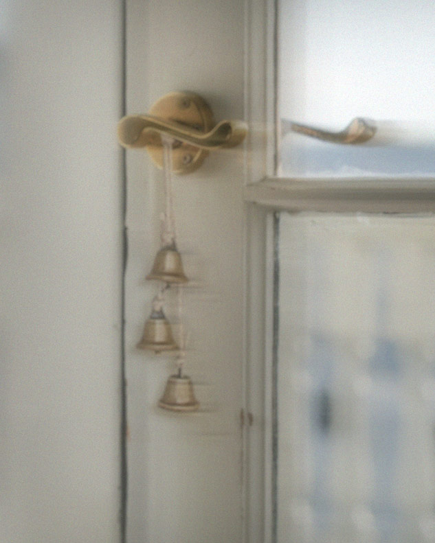bells hand on a white patio door with a glass window after performing the cleansing bell ritual